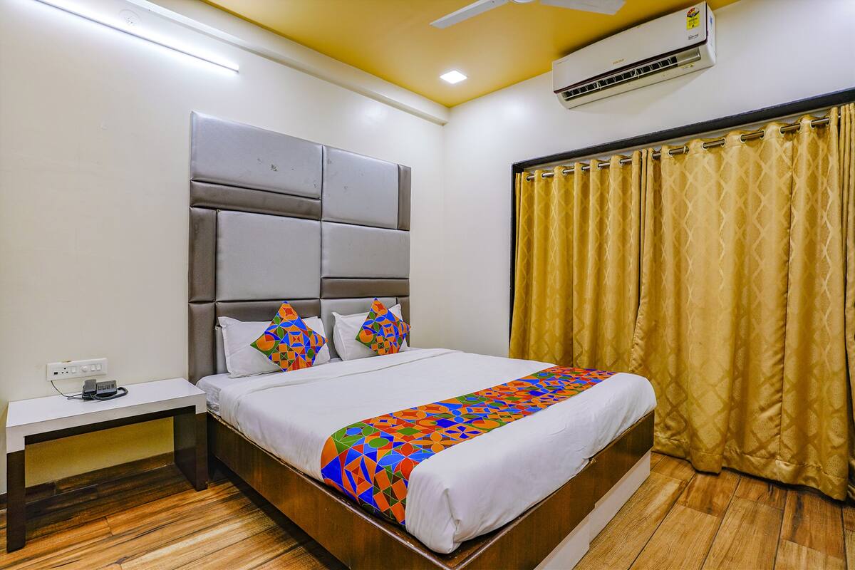 Quarto de hotel com cama, mesa de cabeceira e ar condicionado.