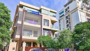Un immeuble à plusieurs étages, sur lequel on peut voir les enseignes « Fab Hotels », « GITANJALI » et « Bed and Breakfast ». Des voitures et une moto sont garées devant.