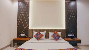 A modern hotel room with a large bed, two bedside tables, and a headboard with geometric patterns. - FabHotel Royal 116 (Noida)