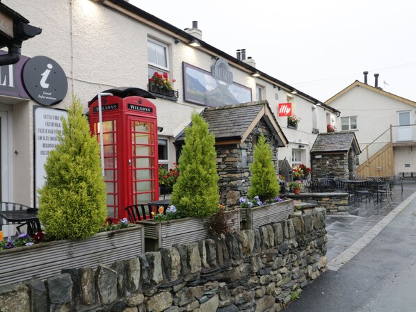 A traditional pub with a red telephone booth, stone walls, and outdoor seating. - 7 Lonsdale Terrace (Penrith)