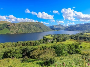 A scenic landscape with a lake, rolling hills, and a small village. - 7 Lonsdale Terrace (Penrith)