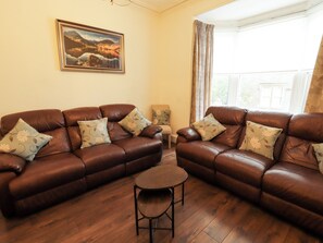 A living room with two brown leather sofas, a small round table, and a framed landscape painting on the wall. - 7 Lonsdale Terrace (Penrith)