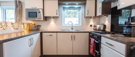 A compact kitchen with a microwave, stove, sink, and cabinets.