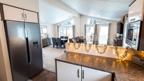 A modern kitchen with a refrigerator, microwave, and a dining area with a table and chairs.