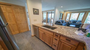 A kitchen with granite countertops, wooden cabinets, and a stainless steel refrigerator. - Quicksilver 1628 (Keystone)