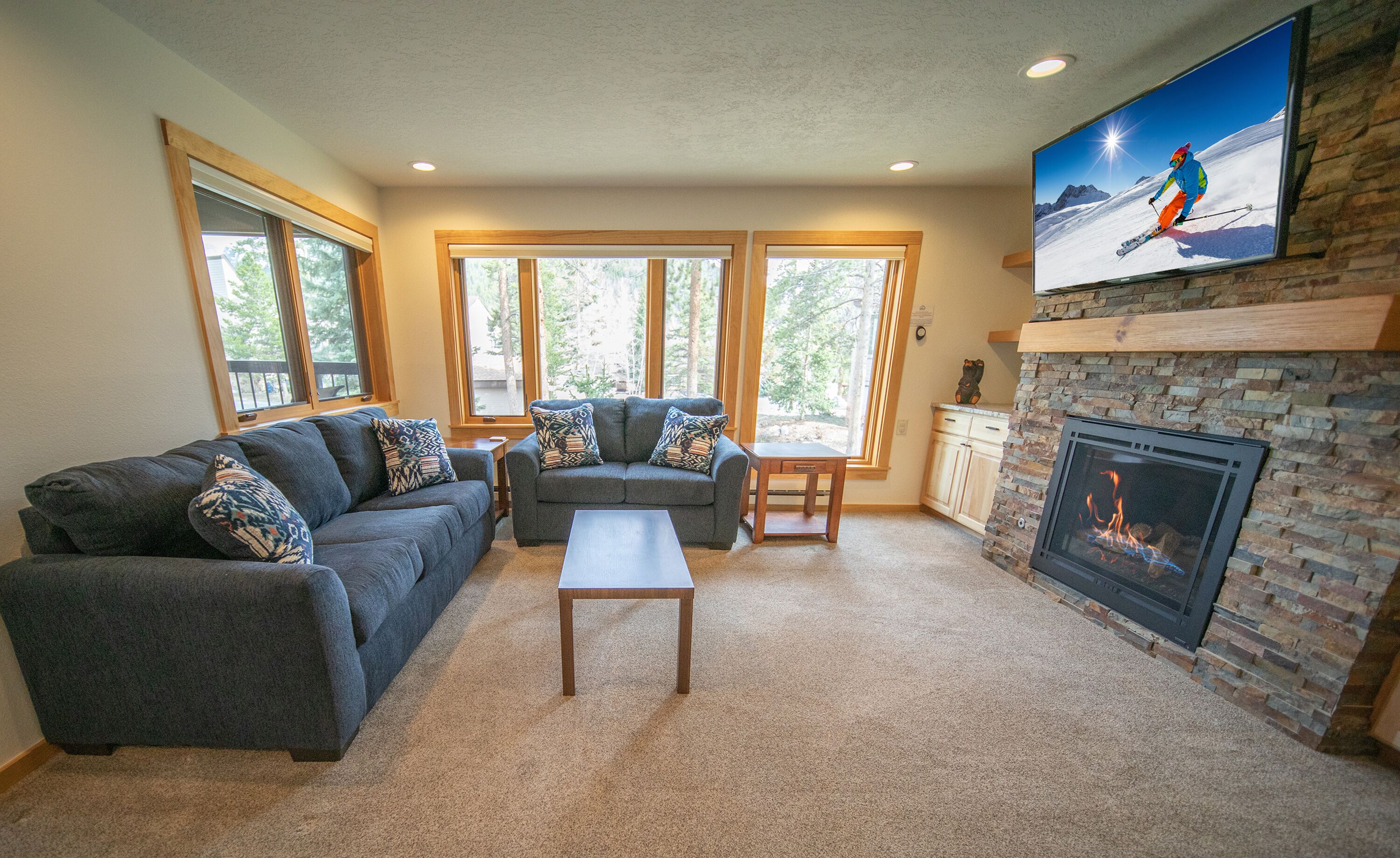 A living room with a fireplace, a sofa set, a coffee table, and a television mounted on the wall.