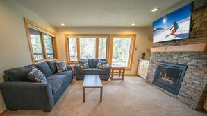 A living room with a fireplace, a sofa set, a coffee table, and a television mounted on the wall. - Quicksilver 1628 (Keystone)