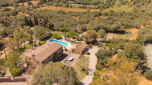 Una villa con piscina, rodeada de olivares y una cancha de tenis.