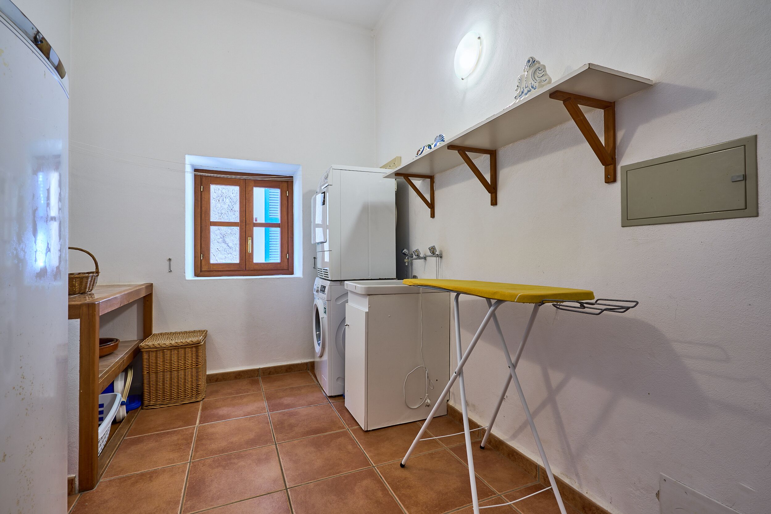 A compact kitchen with a washing machine, a drying rack, and a window.