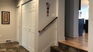Una scala con ringhiera in legno che porta ad un pianerottolo, una porta bianca e un quadro appeso al muro.