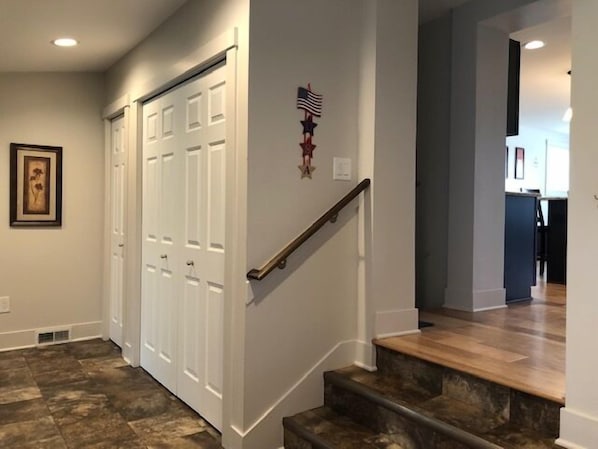 A staircase with a wooden handrail leading to a landing, a white door, and a framed picture on the wall.