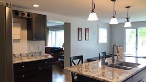 Una cucina moderna con piani in granito, mobili scuri e illuminazione a sospensione.