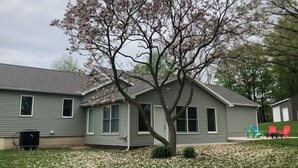 Una casa a due piani con un grande albero nel giardino antistante.