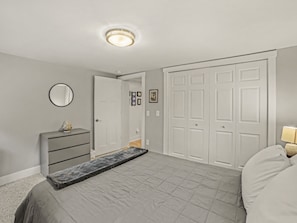 A bedroom with a bed, dresser, wardrobe, and a mirror.
