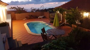 Un pati amb piscina, taula de fusta i cadires.