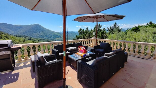 A terrace with wicker furniture, a grill, and a table with drinks and snacks. - Bastide Provençale au Cœur du Massif de L'esterel (FREJUS)