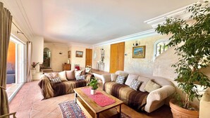 A spacious living room with a large sofa, a wooden coffee table, and a potted plant. - Bastide Provençale au Cœur du Massif de L'esterel (FREJUS)
