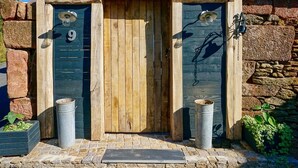 A rustic wooden door with the number 9, flanked by two metal trash cans and a small potted plant. - Eco Gite Les Monts D'amara (CAMPUAC)