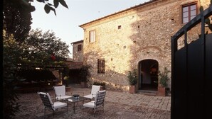 A stone building with a courtyard, featuring a table and chairs, and a door.