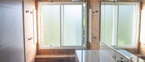 Une salle de bain moderne dotée d’une grande fenêtre, d’une baignoire et d’un espace douche.