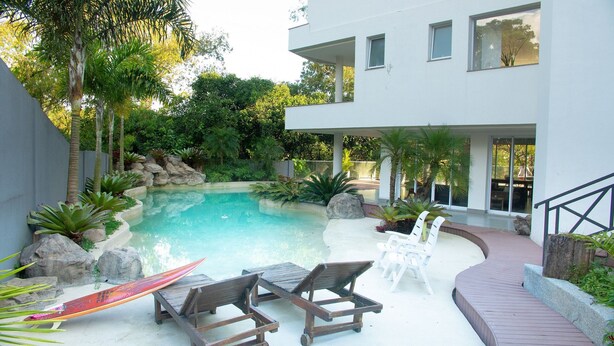 Ein modernes Haus mit Schwimmbad, Liegestühlen und einer Terrassenfläche.