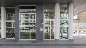 Entrada d'un edifici modern amb portes de vidre, números de porta i un corredor cobert.