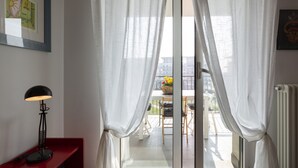 Habitació amb una porta corredissa de vidre, una làmpada de peu negra, un banc vermell i un quadre al mur.