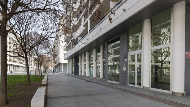 Un edifici modern amb grans finestres de vidre i un passeig net, revestit de rajoles.