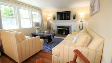 A living room with striped sofas, a fireplace, and a TV mounted above it.