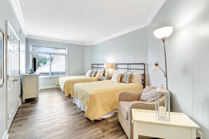 Two single beds with matching headboards, a large window, and a bedside table with lamps.