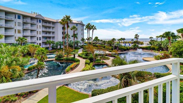 Un resort con varias piscinas, palmeras y un edificio grande con balcones.