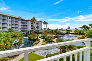 Un resort con varias piscinas, palmeras y un edificio grande con balcones.