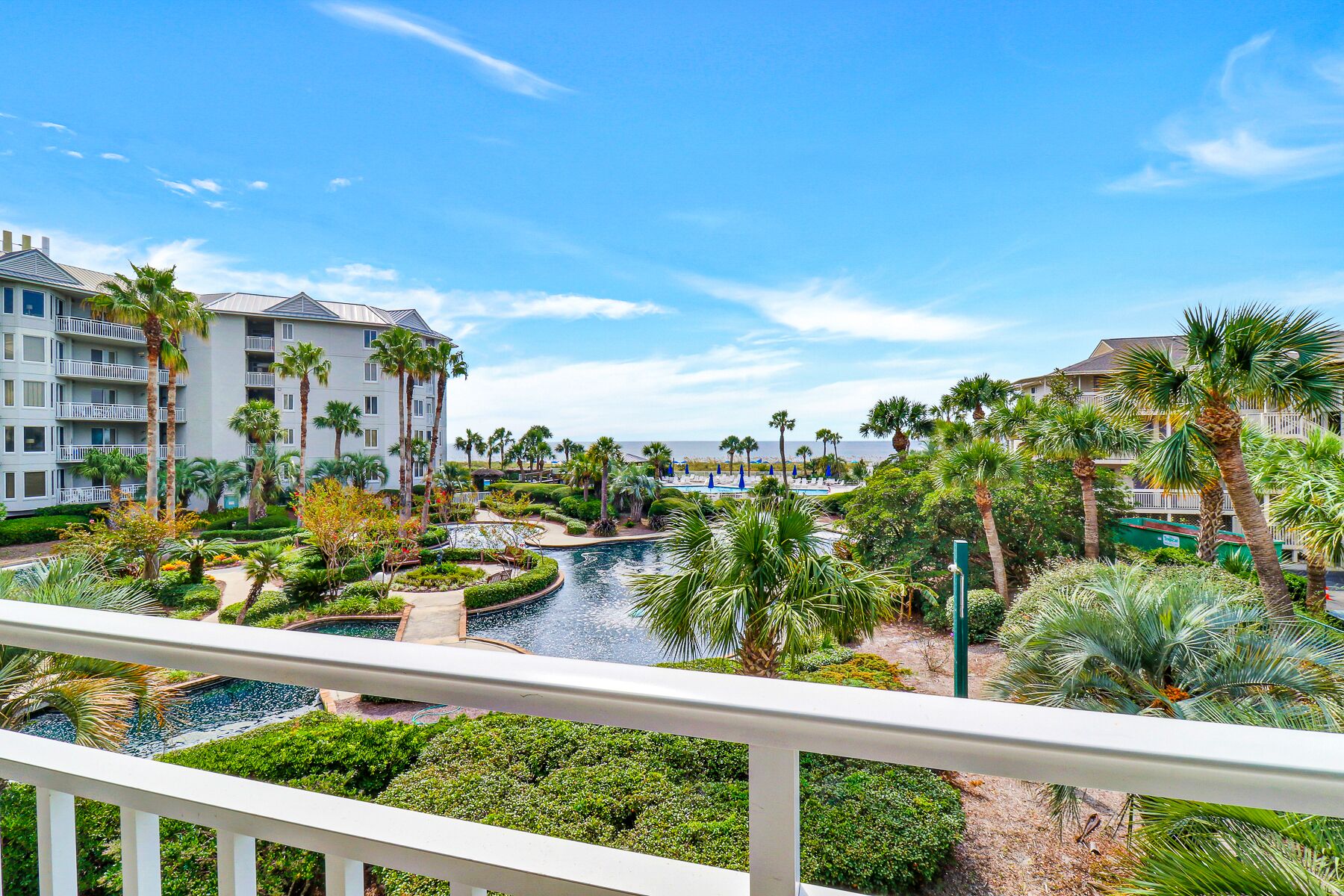 A resort with a pool, palm trees, and a view of the ocean.