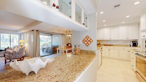 A spacious kitchen with white cabinets, a granite countertop, and a dining area with a table and chairs. - Large Three Bedroom Villa Steps from the Pool! (Hilton Head)
