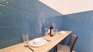 Comedor con mesa de madera dispuesta para dos personas, con platos, vasos y cubiertos.