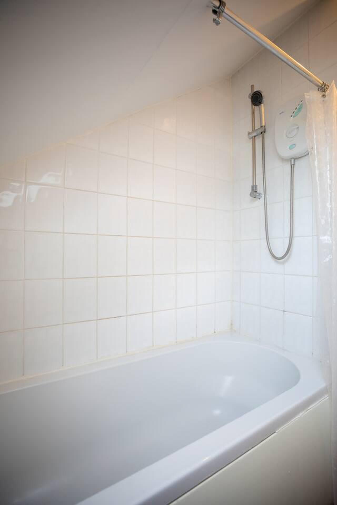 A white bathtub with a showerhead and control panel.