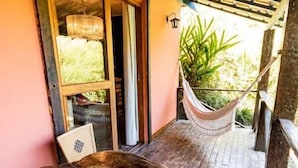 A wooden table with a woven chair, a hammock, and a potted plant on a patio with a wooden pergola overhead. - Pousada Villa 3 Lagos (Santo Antonio do Pinhal)