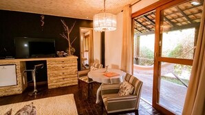 A cozy living room with a stone fireplace, a television, and a dining area with striped chairs and a table. - Pousada Villa 3 Lagos (Santo Antonio do Pinhal)