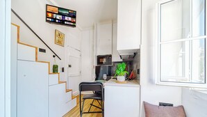 Una cocina compacta con armarios blancos, un microondas y una pequeña isla.