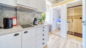 Una cocina moderna con armarios blancos, salpicadero de mármol y una cafetera.
