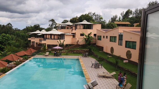 Un hotel con piscina, mobiliario exterior y un exuberante jardín.