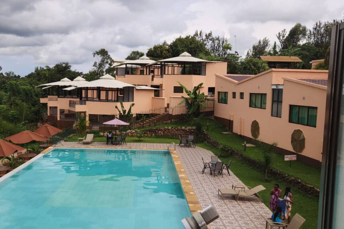 A hotel with a swimming pool, outdoor seating, and a lush garden.