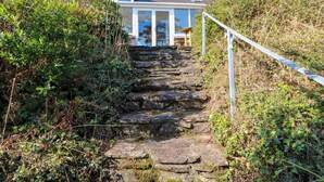 A stone staircase leading to a house with a white railing. - Whispering Pines (Glanlough)