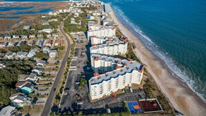 An aerial view of a coastal residential area with beachfront properties, a road, and a beach. - Dolphin's Den | Ocean Views + Community Pools (North Topsail Beach)