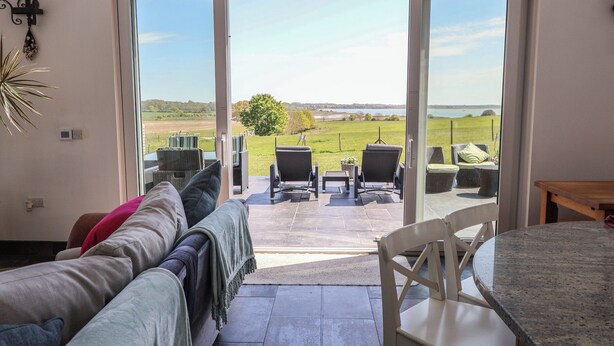 A room with a sliding glass door leading to an outdoor seating area with chairs and a table. - Polly's Annexe (Ipswich)