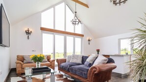 A spacious living room with a high ceiling, large windows, and a cowhide rug. - Polly's Annexe (Ipswich)