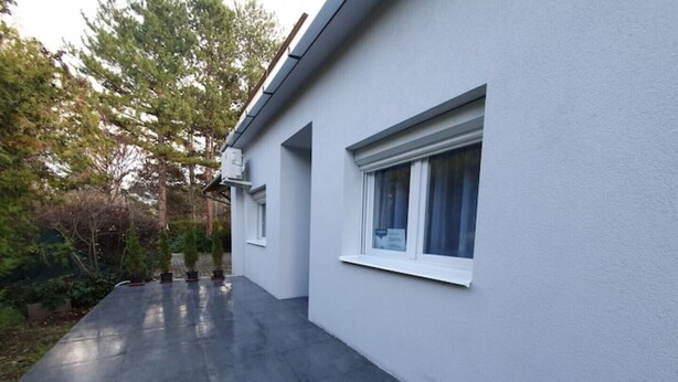 A modern building with a flat roof, a small porch with steps, and a window with a curtain. - Haus mit Garten 2 Minuten von Balaton (Siófok)