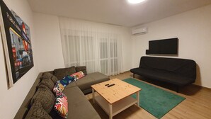 A living room with a sofa, a coffee table, a black couch, a TV, and a poster on the wall. - Haus mit Garten 2 Minuten von Balaton (Siófok)