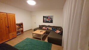 A living room with a wooden wardrobe, a sofa with colorful cushions, a small wooden table, and a green rug. - Haus mit Garten 2 Minuten von Balaton (Siófok)