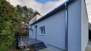 A modern building with a grey exterior, a small window, and a set of steps leading to a door. - Haus mit Garten 2 Minuten von Balaton (Siófok)